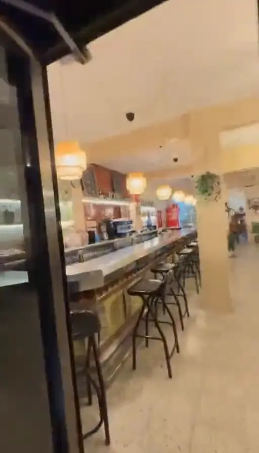 Interior del bar amb barra i tamborets alts